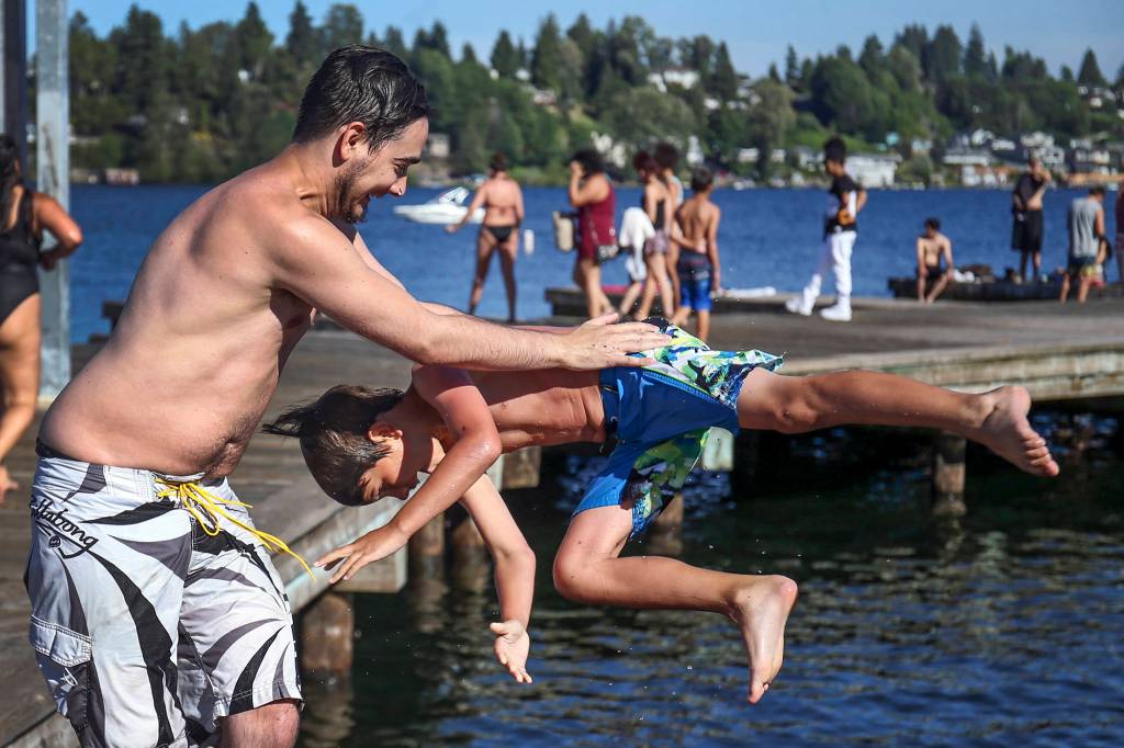 Jordan Rude is tossed into the water by his brother, Stephan Cherewyk, at Wyatt Park in Lake Stevens on July 26. (Kevin Clark / The Herald)