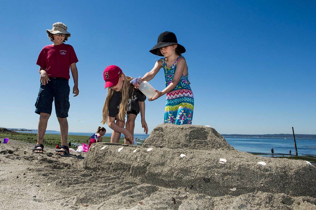 Siblings (from left) Isaac, 12, Sylvie, 10, and Ellery Nelson, 8, build their sand boat they dubbed &ldquo;Pazzaz&rdquo; during the Edmonds Sand Sculpting Contest at Marina Beach on July 25. (Ian Terry / The Herald)