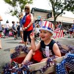 Jackson Emerick, 4, of Shoreline, tosses candy out to crowds lining Main Street in downtown Edmonds during the Edmonds Kind of Fourth Parade on Tuesday. (Ian Terry / The Herald)