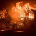 A firefighter sprays water as flames from a wildfire consume a residence near Oroville, California, on Sunday. Evening winds drove the fire through several neighborhoods, leveling homes in its path. (AP Photo/Noah Berger)