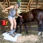 St. Paul Rodeo Queen Melanie Atchison jumps on a bag of shavings as she cleans her horse, Shady&rsquo;s, stall last month. (Molly J. Smith / Statesman-Journal)
