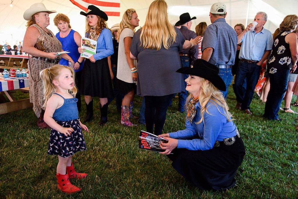St. Paul Rodeo Princess Morgan Spear talks to Jolie Thomas, 3, at a St. Paul Rodeo barbecue last mont. Thomas told Spear that she wants to be a rodeo queen when she grows up. (Molly J. Smith / Statesman-Journal)