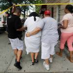 A woman is escorted by officers in plainclothes near the Bronx Lebanon Hospital Center after reports of a shooting Friday in New York. (AP Photo/Julio Cortez)