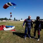 Curtis Zinn (center) lets out a cheer along with his instructor Jordan McElderry (right) after safely landing from a skydive at Skydive Snohomish&rsquo;s Fill the Sky with Hope event to raise money for Housing Hope on Saturday, July 1. (Ian Terry / The Herald)