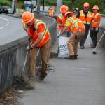 Snohomish County workers clean a sidewalk of trash and debris along Marine Drive in Marysville on June 28. (Ian Terry / The Herald)