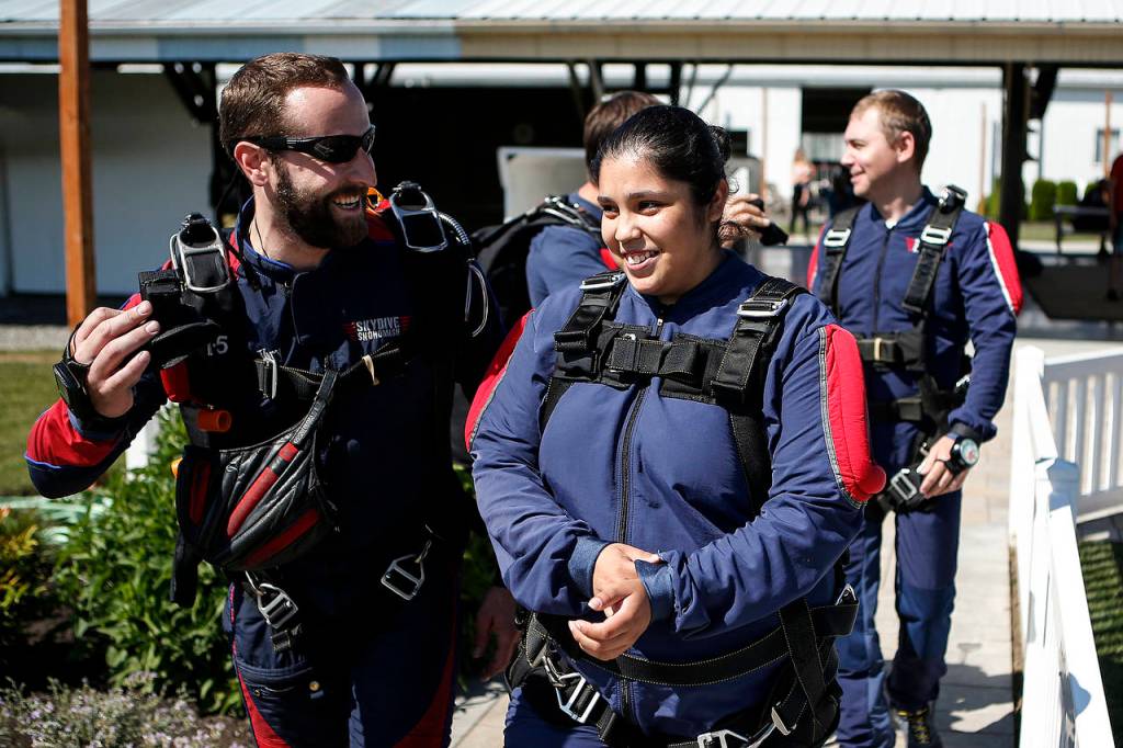Yessica Ramos (right) is led by her instructor out to a waiting plane before skydiving at Skydive Snohomish&rsquo;s Fill the Sky with Hope event on Saturday, July 1. (Ian Terry / The Herald)