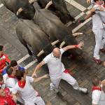 Revellers run in front of fighting bulls during the second running of the bulls at the San Fermin Festival in Pamplona, Spain, on Saturday. (AP Photo/Alvaro Barrientos)