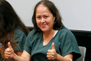 Mother accused of slaying her family smiles in court