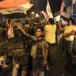 Iraqi security and civilians celebrate while holding national flags as they wait for the final announcement of the defeat of the Islamic state militants, in Basra, Iraq, on Sunday.(AP Photo/Nabil al-Jurani)