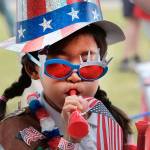 Hana Cho, 8, of Girl Scout Troop 5665, tests out a horn prior to participating the Fourth of July parade in Santa Monica, California, on Tuesday. Decked out in red, white and blue, Californians waved flags and sang patriotic songs at Independence Day parades across the state. (AP Photo/Richard Vogel)