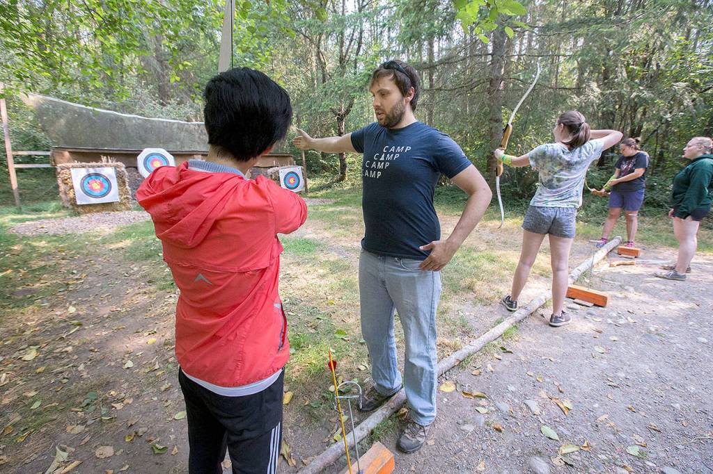 Program Director Erik Lindros shows a camper how to stand properly to aim a bow during an archery class at Camp Killoqua Tuesday in Stanwood. Lindros is in his fourth year as program director. (Andy Bronson / The Herald)