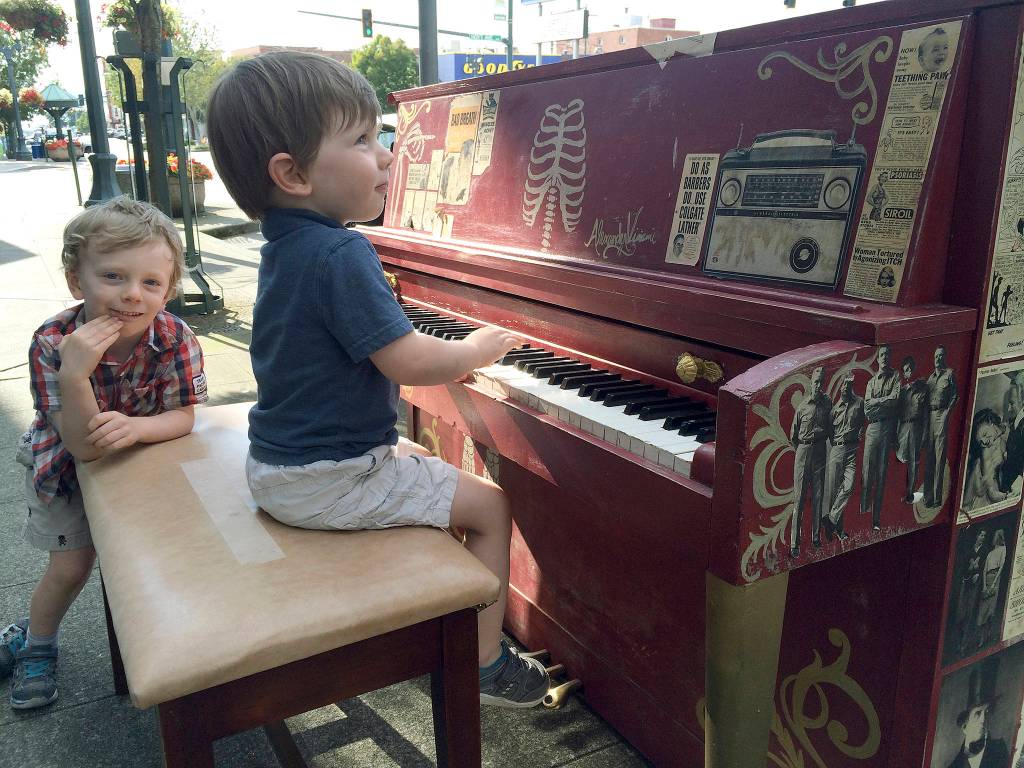 Rigsby, 4, and Kesler, 3, Douey of Canada test out one of the Street Tunes pianos while visiting Everett with their parents earlier this week. (Gale Fiege / The Herald)