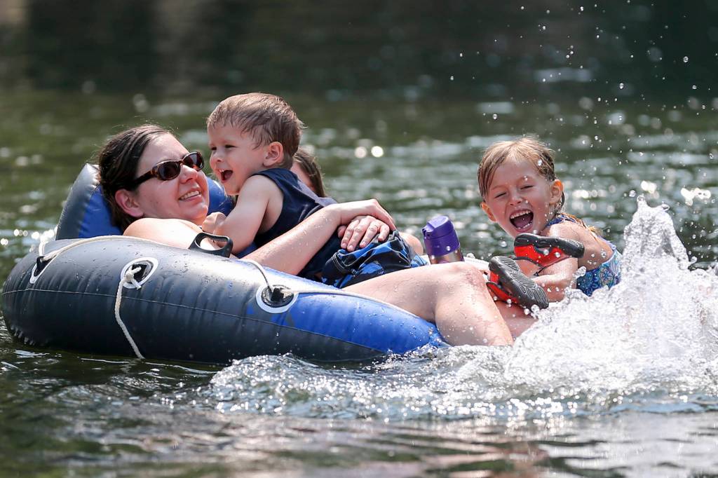 Sarah Schurman, holding Ford Schurman, 3, and Jordan Nettles, 5, play in the waters of the Pilchuck River in Machias on Aug. 2. (Kevin Clark / The Herald)