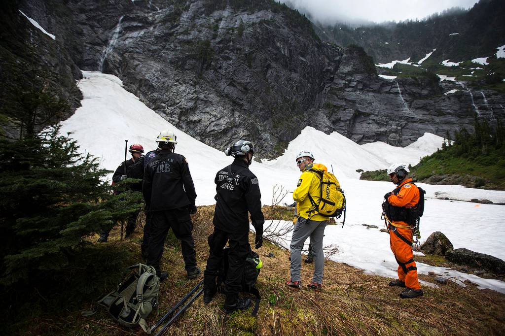 Snohomish County Search and Rescue members, including Oyvind Henningsen (center right), wait to be lifted out of their location via helicopter during training at the Big Four Ice Caves on June 10. (Ian Terry / The Herald)