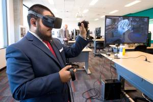 Sharief Yusuf waves as he uses a 3-D simulator during an open house at the Washington State University Everett building on Tuesday, Aug. 15, 2017 in Everett, Wa. The 3-D units will allow students with a fear of speaking to use it to simulate talking in front of an audience when taking Communication classes. (Andy Bronson / The Herald)