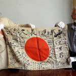 WWII veteran Marvin Strombo (right), and Obon Society executives director Rex Zika hold up the Japanese flag with names written on it in Portland, Oregon, on Aug. 7. (AP Photo/Don Ryan)