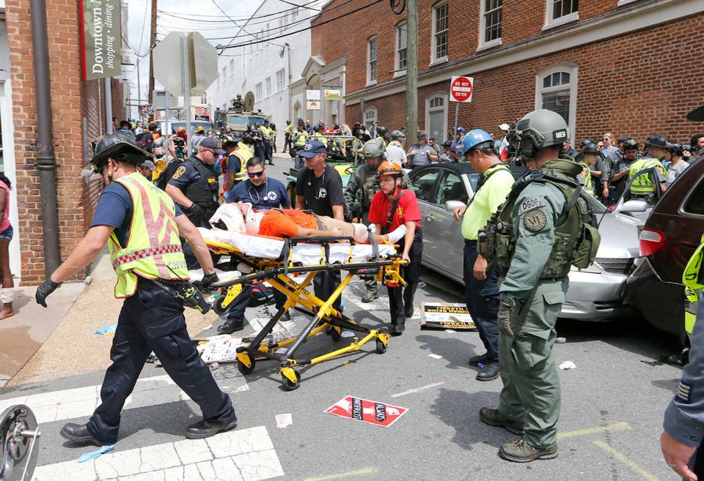 Rescue personnel help injured people after a car ran into a large group of protesters after an white nationalist rally in Charlottesville, Virginia, on Saturday. (AP Photo/Steve Helber)