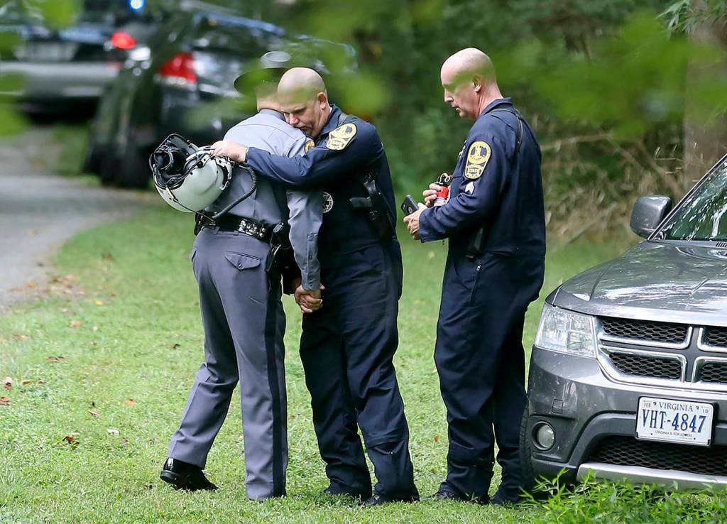 Authorities embrace while working near the scene of a deadly helicopter crash near Charlottesville, Virginia, on Saturday. (Shelby Lum/Richmond Times-Dispatch via AP)
