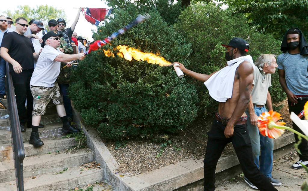A counter demonstrator uses a lighted spray can against a white nationalist demonstrator at the entrance to Lee Park in Charlottesville, Virginia, on Saturday. (AP Photo/Steve Helber)