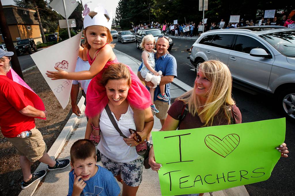 Talia, 4, rides on the shoulders of her mother, Nicki Berger, a teacher at Terrace Park School in Mountlake Terrace, during a rally outside Edmonds School District offices Aug. 8 to highlight ongoing struggles with contract negotiations. (Ian Terry / The Herald)
