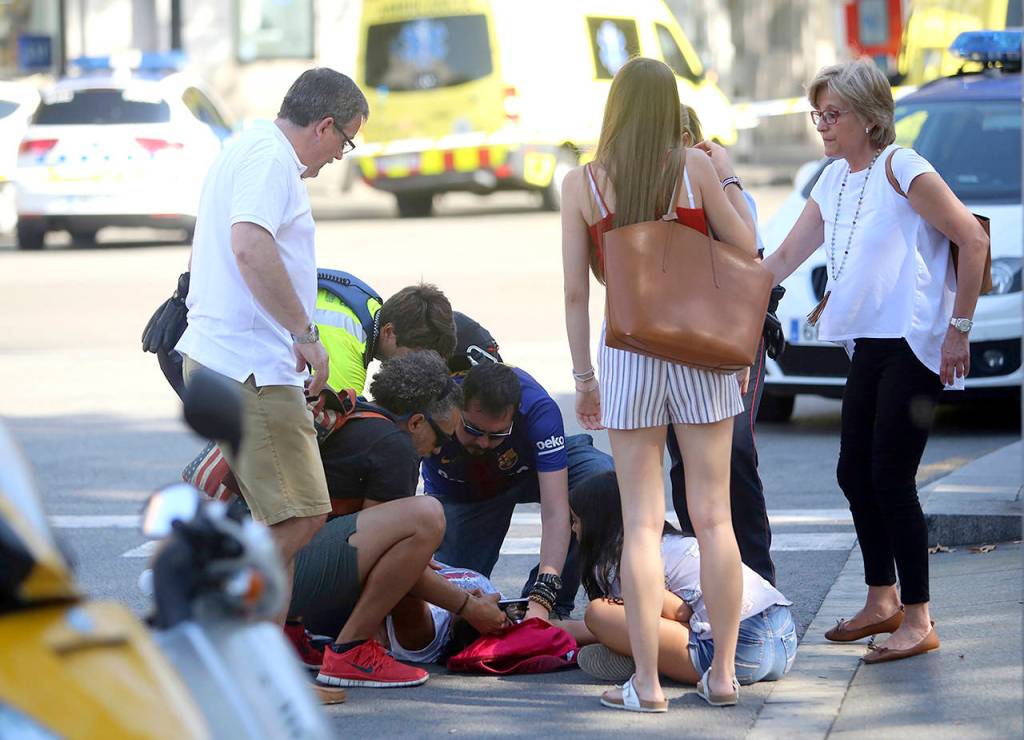 An injured person is treated in Barcelona, Spain, on Thursday after a white van jumped the sidewalk in the historic Las Ramblas district, crashing into a summer crowd of residents and tourists and injuring several people, police said. (AP Photo/Oriol Duran)