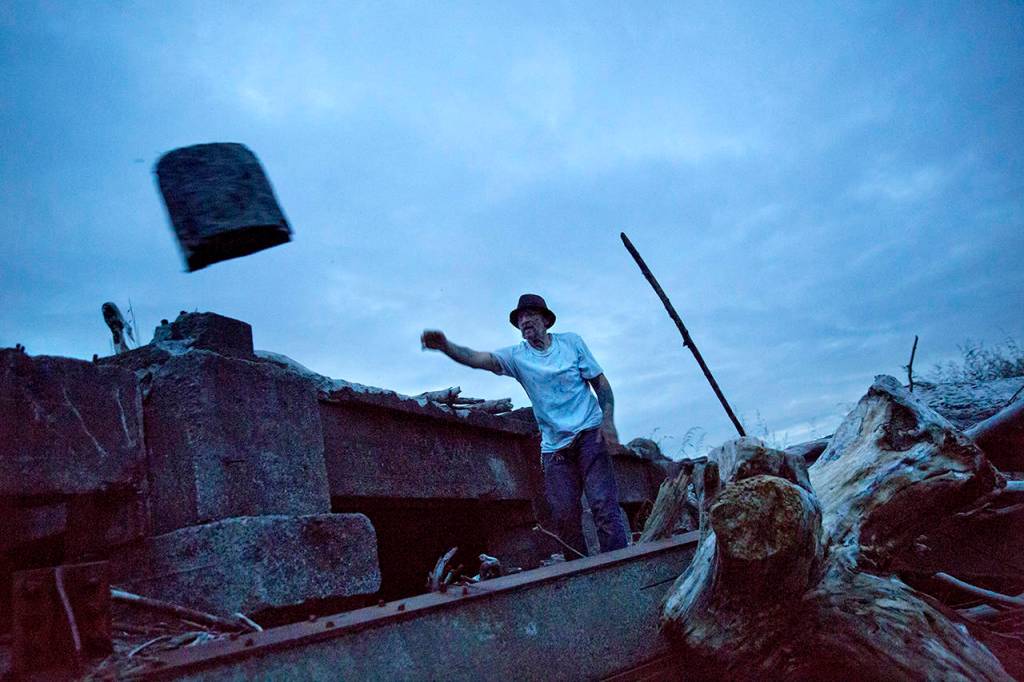 Scott Stevens collects wood from the shore to light a fire in a homeless encampment, where he lives along the river, in Aberdeen on June 14. (AP Photo/David Goldman)