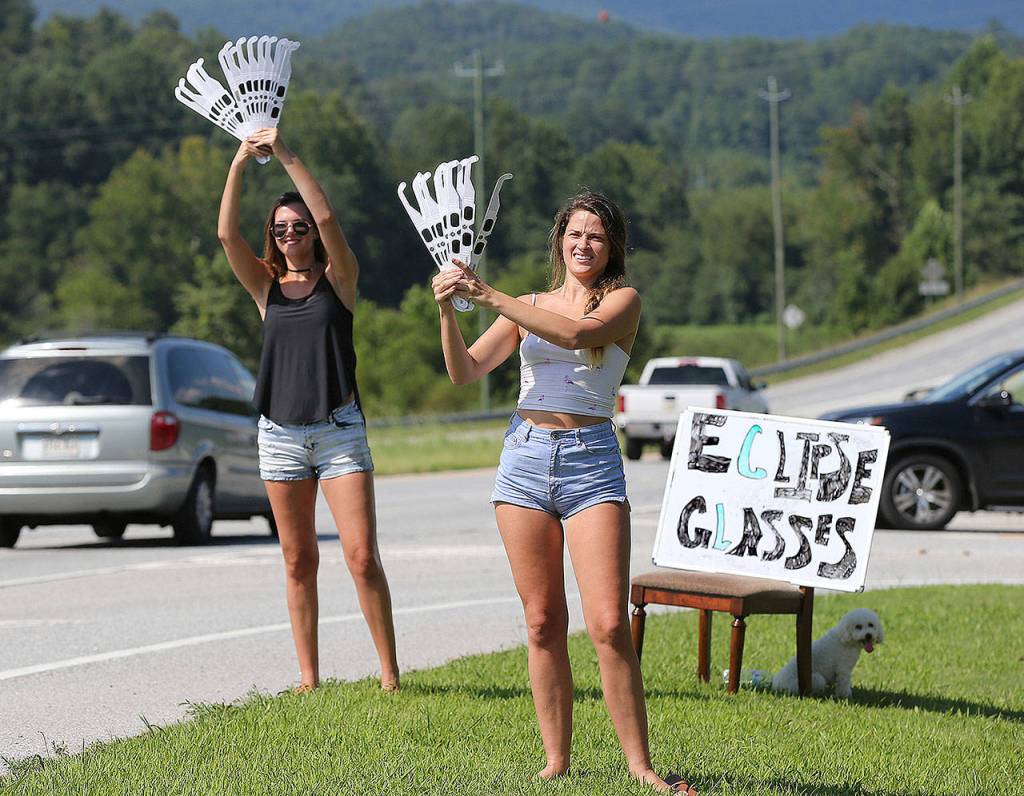 Ashley Ann Sander (left) and Alexandra Dowling hawk solar eclipse glasses for $10 a pair on the side of the road approaching Clayton, Georgia, on Sunday. (Curtis Compton/Atlanta Journal-Constitution via AP)
