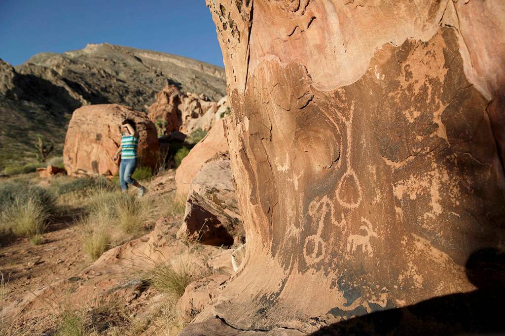 In this May 26 photo, Susie Gelbart walks near petroglyphs at the Gold Butte National Monument near Bunkerville, Nevada. (AP Photo/John Locher, File)