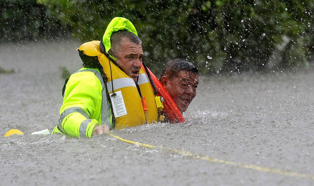 Wilford Martinez (right) is rescued from his flooded car by Harris County Sheriff&rsquo;s Department Richard Wagner along Interstate 610 in floodwaters from Tropical Storm Harvey on Sunday in Houston, Texas. (David J. Phillip / Associated Press)