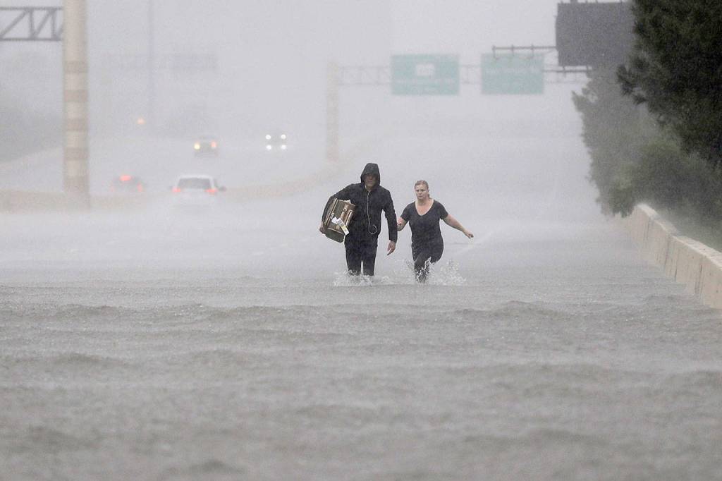 Two people walk down a flooded section of Interstate 610 in floodwaters from Tropical Storm Harvey on Sunday in Houston, Texas. (David J. Phillip / Associated Press)
