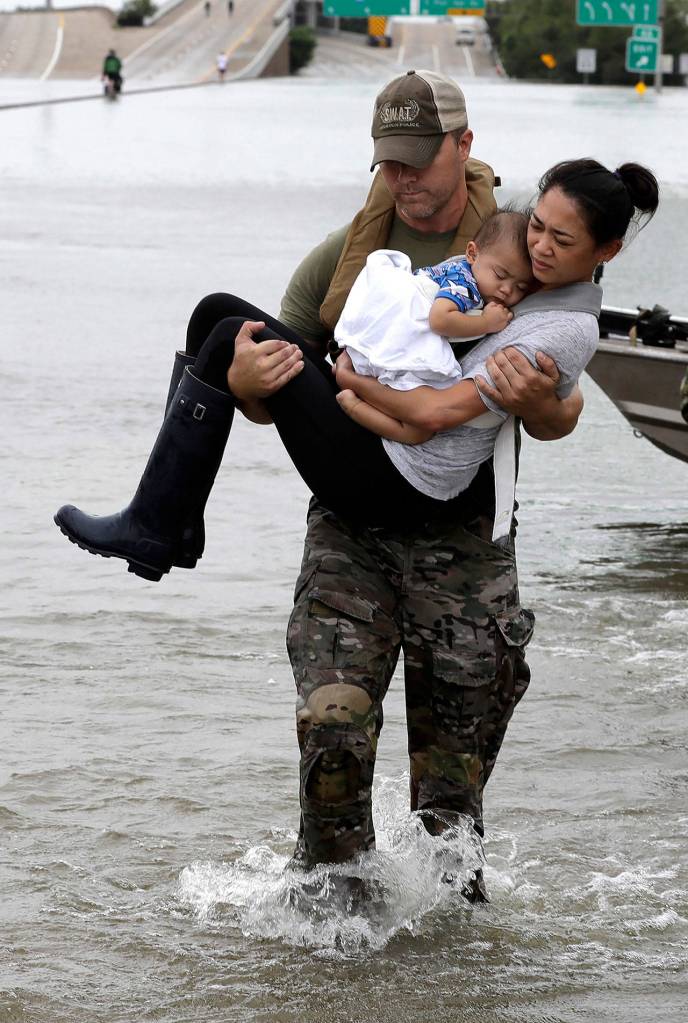 Houston Police SWAT officer Daryl Hudeck carries Catherine Pham and her 13-month-old son Aiden after rescuing them from their home surrounded by floodwaters from Tropical Storm Harvey on Sunday in Houston. (AP Photo/David J. Phillip)