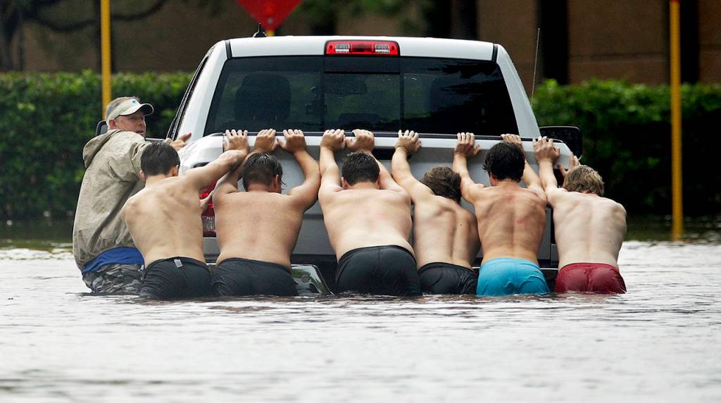 People push a stalled pickup through a flooded street in Houston, after Tropical Storm Harvey dumped heavy rains on Sunday. (AP Photo/Charlie Riedel)