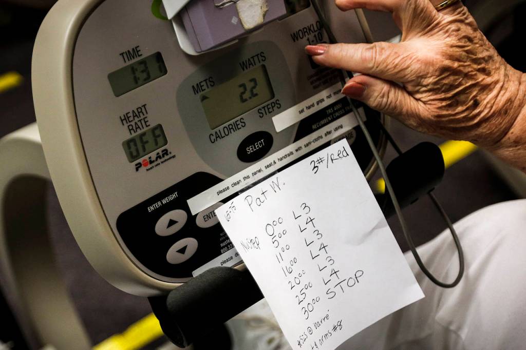 Pat Ward adjusts the workload on her seated step machine to correspond with her assigned workout during a cardiovascular rehabilitation class at Providence Regional Medical Center Everett on Sept. 6. (Ian Terry / The Herald)