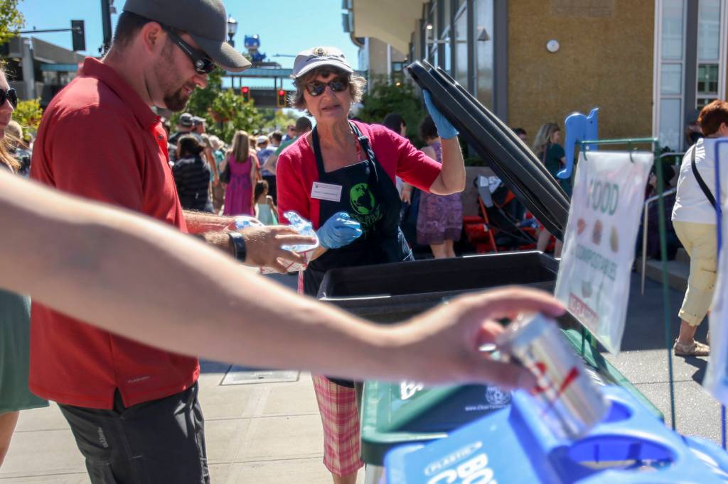 Photos by Kevin Clark / The Herald                                Nancy Vandenberg directs the correct sorting of waste during the Everett Food Truck festival Aug. 26.