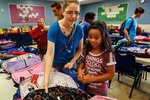 Rachel Preston helps Jailey Henson, 10, pick out a brand new backpack for school Thursday at the Everett Boys & Girls Club. Preston recently joined a new Rotary club for young people wanting to get involved and help out in the community. (Dan Bates / The Herald)