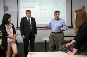 University of Washington Bothell&rsquo;s forensic accounting class students Yiya You (left) and Rochelle McElroy (right) talk with professor Rajib Doogar (center right) and class mentor Kenneth Hines, a former IRS investigator. (Ian Terry / The Herald)
