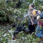 Heather Craig carries her 23-month-old son Bryant as Gabby Hollingsworth, 16, carries Craig&rsquo;s 6-month-old daughter Kaisley away from their home along Highway 18 in Fayette, Alabama, after a tornado went through Fayette County on Thursday. (Erin Nelson/The Tuscaloosa News via AP)