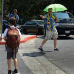 Josh Defeo wears an aloha shirt beneath the shade of an umbrella while directing the traffic of parents who came to pick up their children early at Orinda Intermediate School on Friday, Sept. 1, 2017, in Orinda, Calif. Dozens of cooling centers opened throughout California, schools let students out early and outdoor events were cancelled as temperatures soared from a heat wave expected to last through the Labor Day weekend. (AP Photo/Ben Margot)