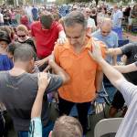 Church members gather to pray around flood victim Carlos Ochoa during Sunday service in the parking lot of the First Baptist Church Sunday in Humble, Texas. The church building was flooded with two feet of water from Hurricane Harvey prompting services to be held in the parking lot. (AP Photo/Charlie Riedel)