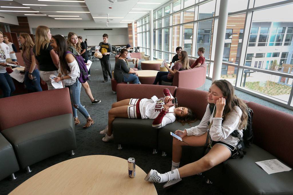 Finding a spot on the new couches in the library, juniors Kylee Ditto and Mia Barrio check their phones as they take a tour, then attend class, at the new Lakewood High School building on Wednesday in Lakewood. (Andy Bronson / The Herald)