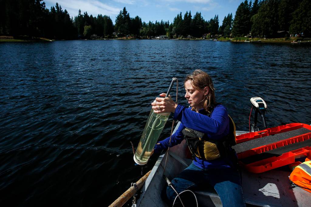 Marisa Burghdoff, a water quality specialist with Snohomish County, pulls up a water sample from Lake Ketchum during testing Sept. 13. (Ian Terry / The Herald)