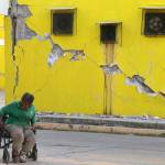 A man sits in his wheelchair backdropped by a building damaged in a massive earthquake, in Juchitan, Oaxaca state, Mexico on Friday. (AP Photo/Luis Alberto Cruz)