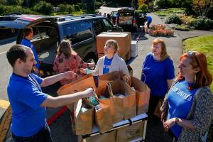 Fluke Corp.&rsquo;s Susan Israel (center) assists with other Fluke employees including William Nelson (left) and Allyce Barry (right), in efforts to load 260 new-mom kits into vehicles outside the company Friday morning. Workers volunteered with United Way&rsquo;s Day of Caring. (Dan Bates / The Herald)