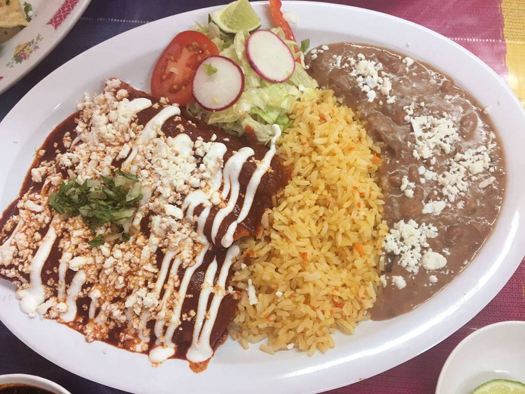 Chicken enchiladas with red sauce, cheese and crema, plus rice and beans makes for a seriously filling dish at Ade&rsquo;s Mexican Deli. (Ben Watanabe / The Herald)
