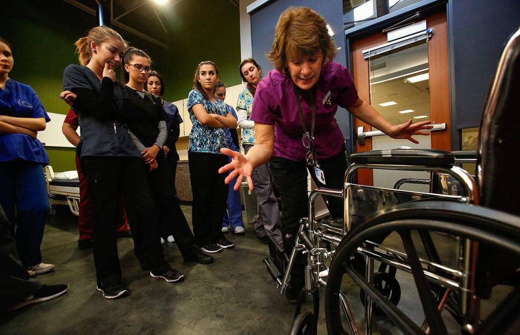On her second day on the job, on Wednesday, assistant instructor Marilyn Pyles, RN, explains to new students in the nursing assistants program at Sno-Isle how to properly set up and adjust a wheelchair for a patient. (Dan Bates / The Herald)