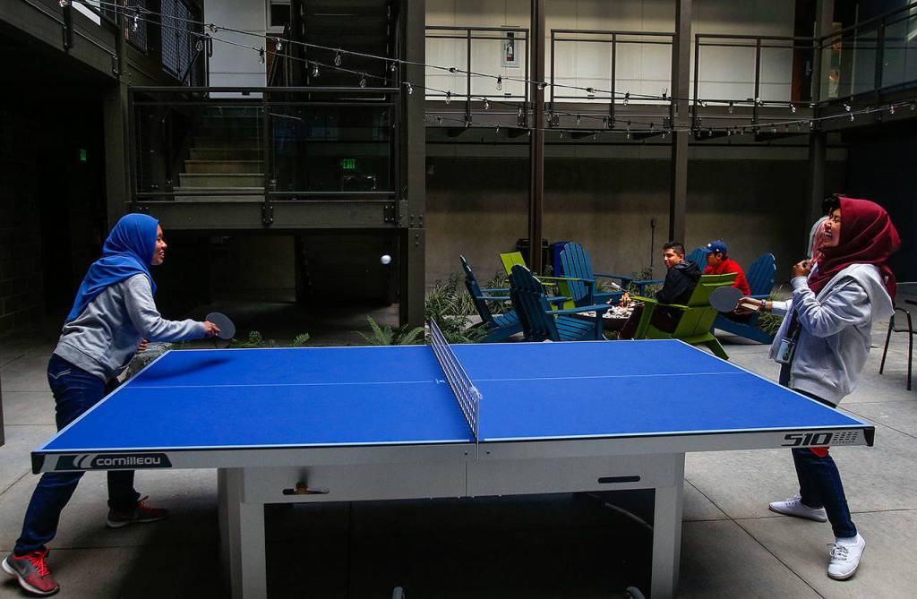 Allisya Khairil, 19, plays ping pong with her friend Nadia Kamarudin, a resident assistant at Cedar Hall. The open-air courtyard has a gas fire pit, outdoor lighting, a TV lounge and laundry facilities. Every apartment opens onto the courtyard. (Dan Bates / The Herald)