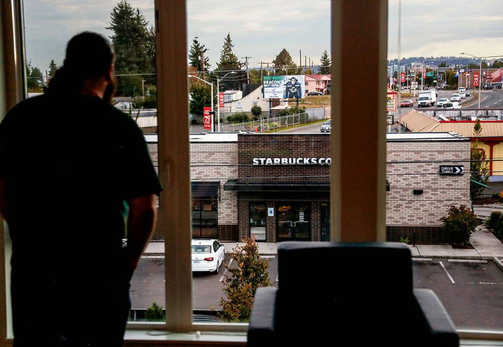 Chris Reilly, 22, looks out from his apartment on the third floor of Cedar Hall. A coffee drinker, he is glad to be located so near a Starbucks along the southern edge of the EvCC campus. (Dan Bates / The Herald)
