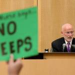 A protester holds a sign as Seattle City Council member Tim Burgess speaks. He was chosen on Monday by the Seattle City Council to be temporary mayor. (Ken Lambert/The Seattle Times via AP)