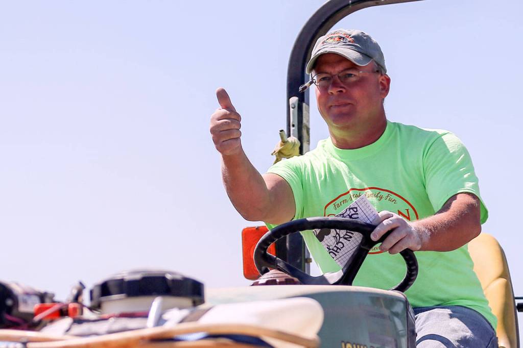 Darren Carleton thumbs up his wife, Georgina Carleton, while they work to layout the corn maze Saturday morning at Carleton Farms in Lake Stevens on July 15, 2017. (Kevin Clark / The Herald)