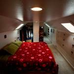A cozy bedroom, bath and office in the finished attic boasts built-in shelving, drawers and skylights.